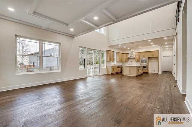 unfurnished living room featuring beam ceiling, a high ceiling, dark hardwood / wood-style floors, and coffered ceiling