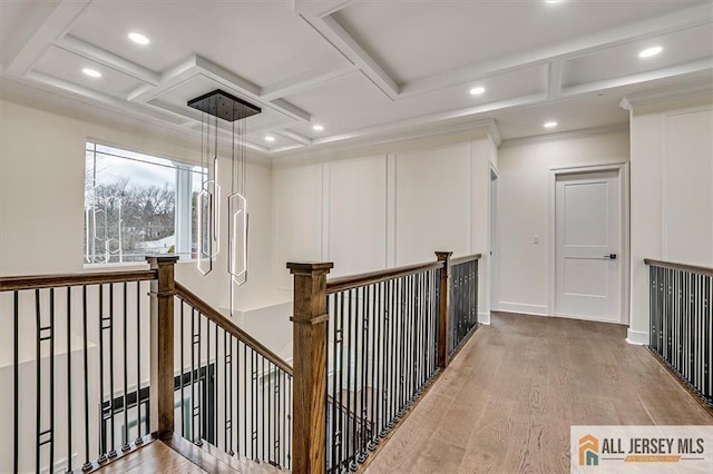 corridor with beamed ceiling, crown molding, wood-type flooring, and coffered ceiling