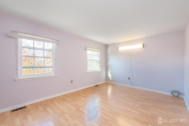 unfurnished room featuring light hardwood / wood-style floors and plenty of natural light