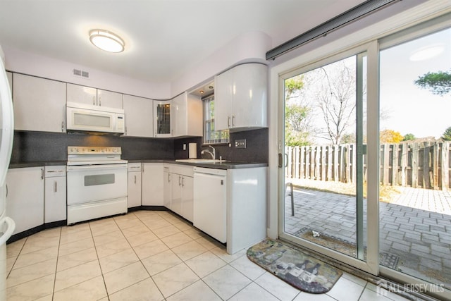 kitchen with white appliances, light tile patterned floors, decorative backsplash, white cabinets, and sink