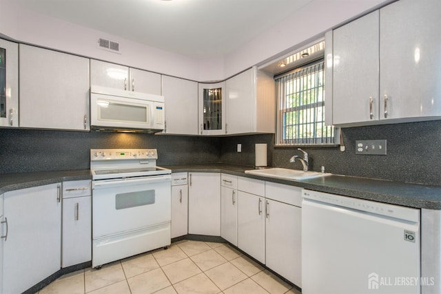 kitchen with sink, white cabinetry, light tile patterned floors, white appliances, and decorative backsplash