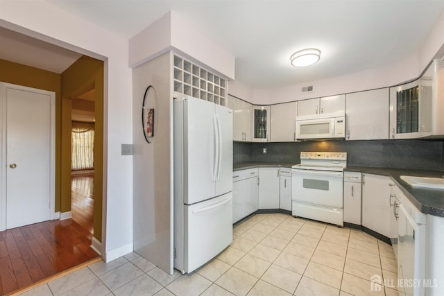 kitchen with white appliances, white cabinetry, light tile patterned floors, and tasteful backsplash