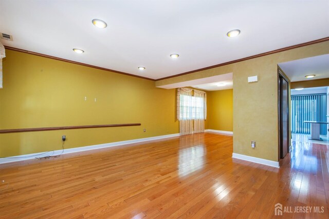 unfurnished room with light wood-type flooring and crown molding