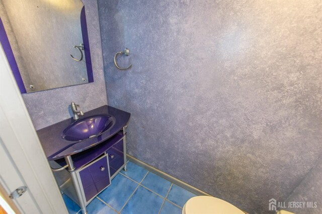 bathroom with toilet, tile patterned flooring, and vanity