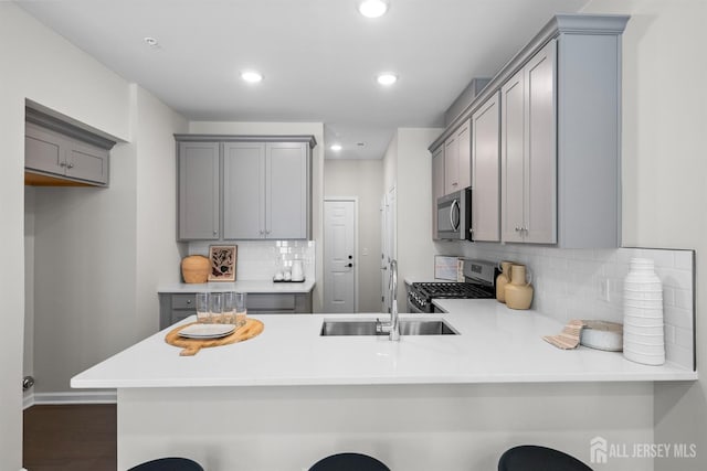 1305 Parker Blvd, West Windsor, NJ 08550 - kitchen featuring stainless steel appliances, gray cabinetry, a sink, decorative backsplash, and a peninsula