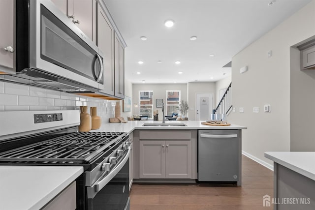 1305 Parker Blvd, West Windsor, NJ 08550 - kitchen featuring appliances with stainless steel finishes, a peninsula, gray cabinets, a sink, and decorative backsplash