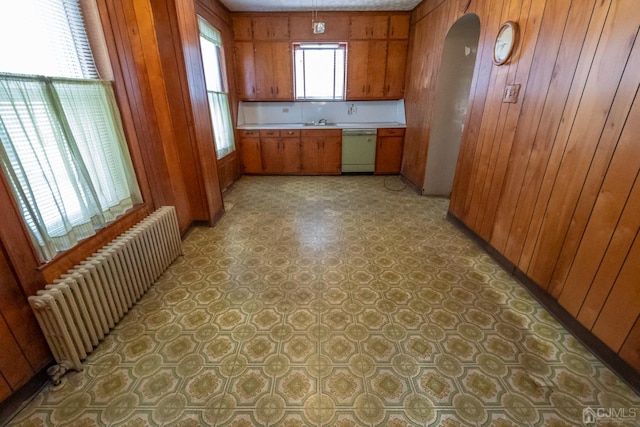 kitchen with radiator heating unit, white dishwasher, and wooden walls