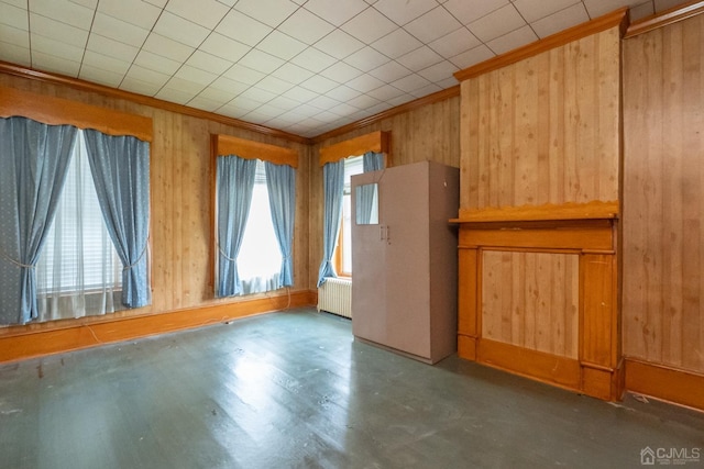 empty room featuring radiator, wooden walls, and crown molding