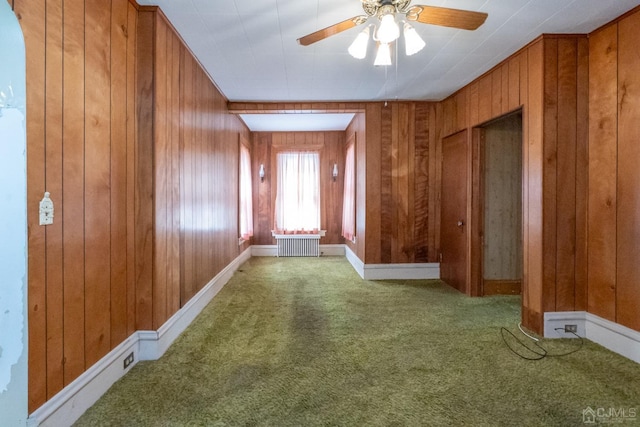 hall featuring wood walls, radiator heating unit, and carpet