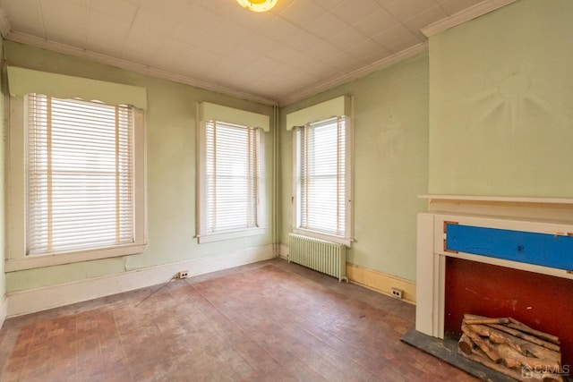 unfurnished living room featuring radiator heating unit, hardwood / wood-style floors, and ornamental molding