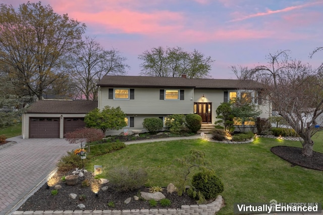 raised ranch featuring a yard, decorative driveway, and an attached garage