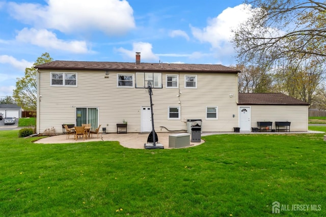 rear view of house featuring a patio area, a yard, and a chimney