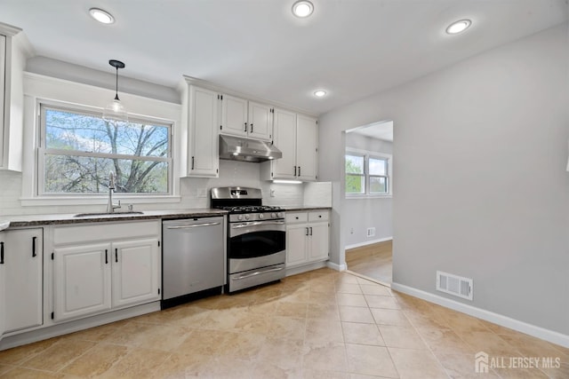 kitchen featuring a sink, stainless steel appliances, backsplash, under cabinet range hood, and visible vents