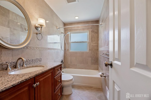 full bathroom featuring vanity, toilet, tile patterned floors, shower / bath combination, and tile walls