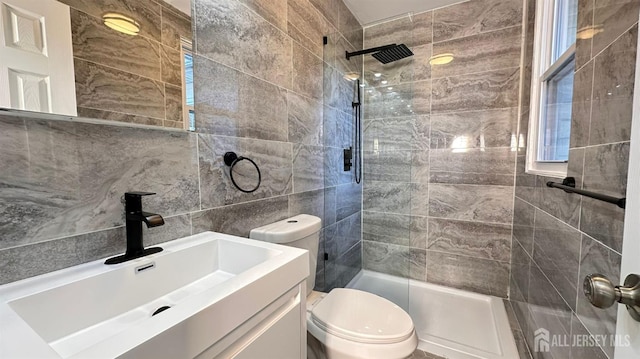 bathroom with vanity, tile walls, toilet, and a tile shower