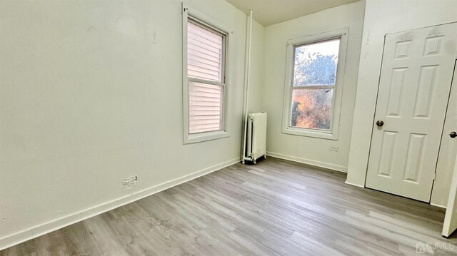 unfurnished bedroom with light hardwood / wood-style floors and radiator