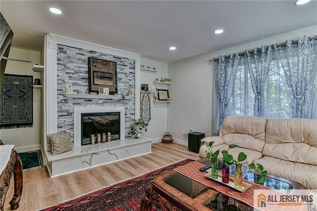 living room with a stone fireplace and light hardwood / wood-style floors