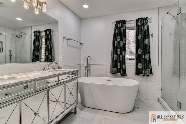 full bath featuring marble finish floor, a freestanding bath, vanity, a shower stall, and recessed lighting