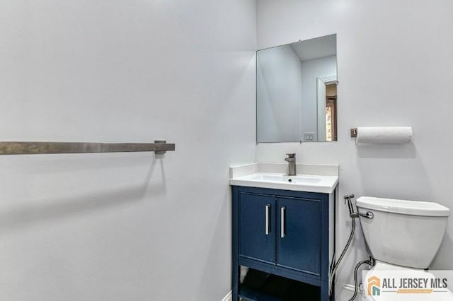 half bath featuring baseboards, vanity, and toilet