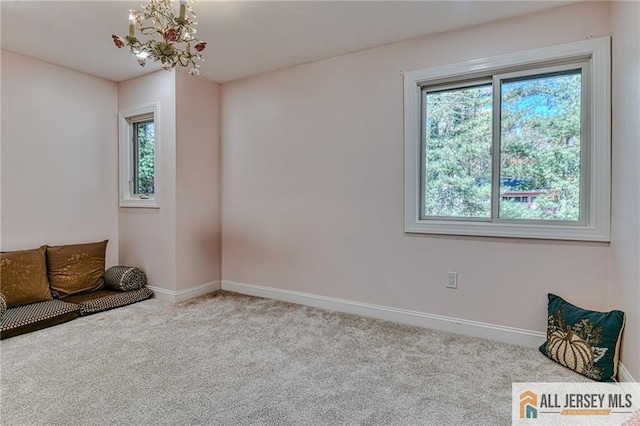 unfurnished room featuring a chandelier, carpet flooring, and baseboards