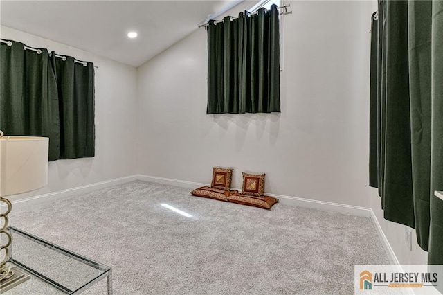 carpeted empty room featuring recessed lighting, lofted ceiling, and baseboards