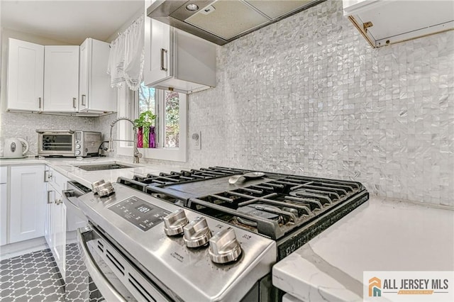 kitchen with light stone countertops, white cabinetry, decorative backsplash, and extractor fan