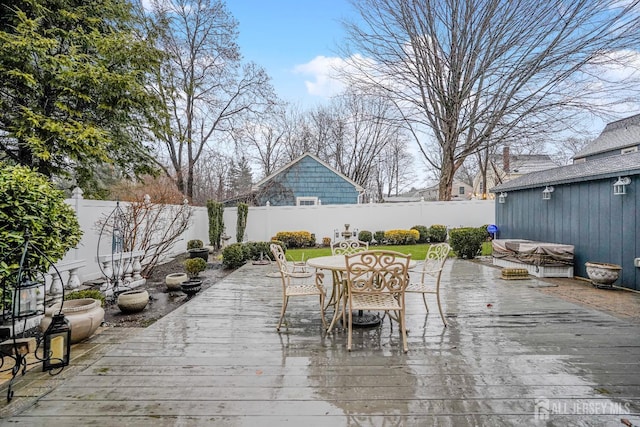 wooden deck with outdoor dining area and a fenced backyard