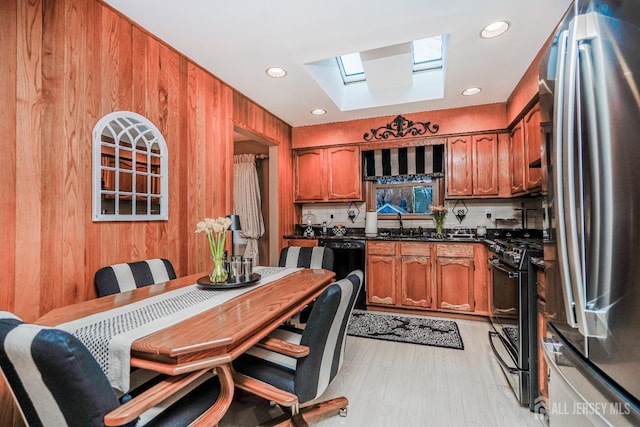 kitchen featuring light wood-style flooring, brown cabinets, black appliances, and a skylight