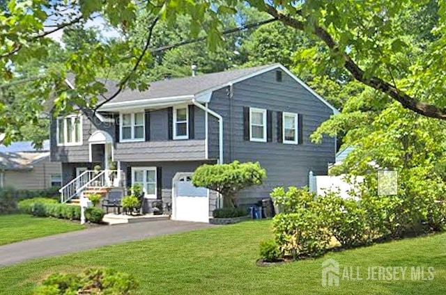 split foyer home featuring a garage, a front lawn, and driveway