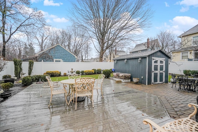 wooden deck with an outbuilding, a storage unit, outdoor dining area, and a fenced backyard