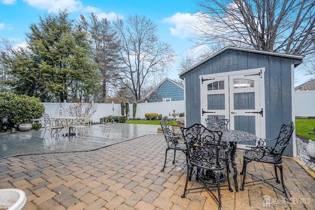 view of patio featuring outdoor dining space, an outdoor structure, a storage unit, and a fenced backyard