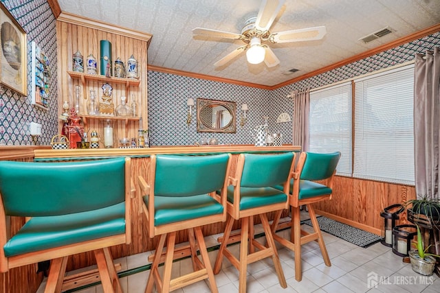 bar featuring a ceiling fan, visible vents, wallpapered walls, ornamental molding, and a dry bar