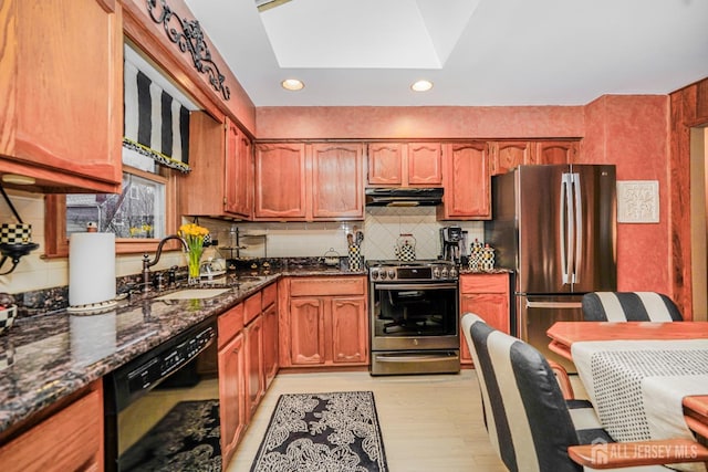 kitchen with dark stone counters, a sink, decorative backsplash, stainless steel appliances, and under cabinet range hood