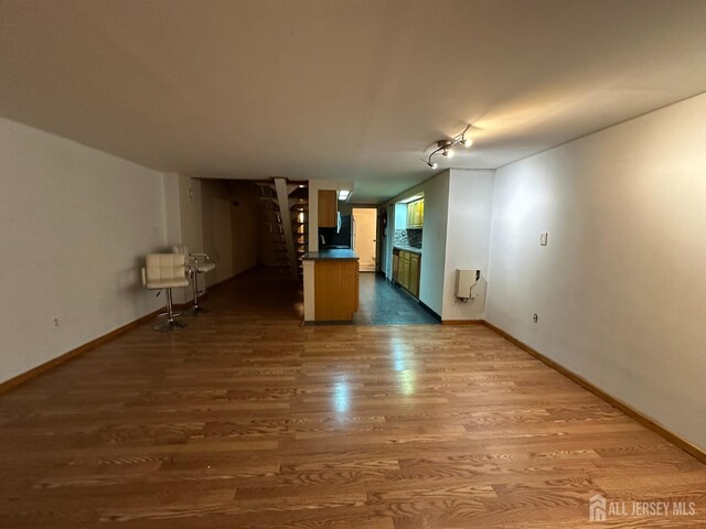 unfurnished living room with heating unit and hardwood / wood-style floors