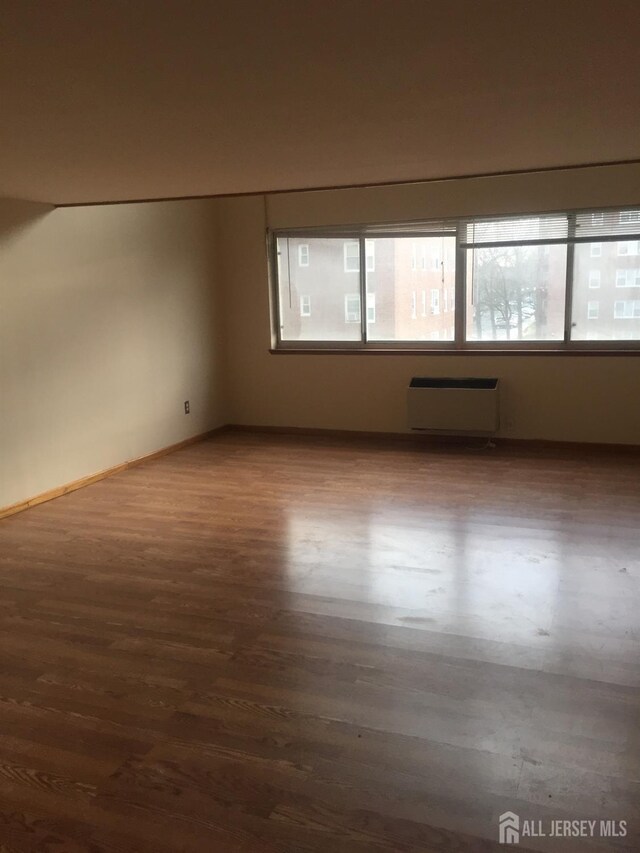 empty room with dark hardwood / wood-style flooring and radiator