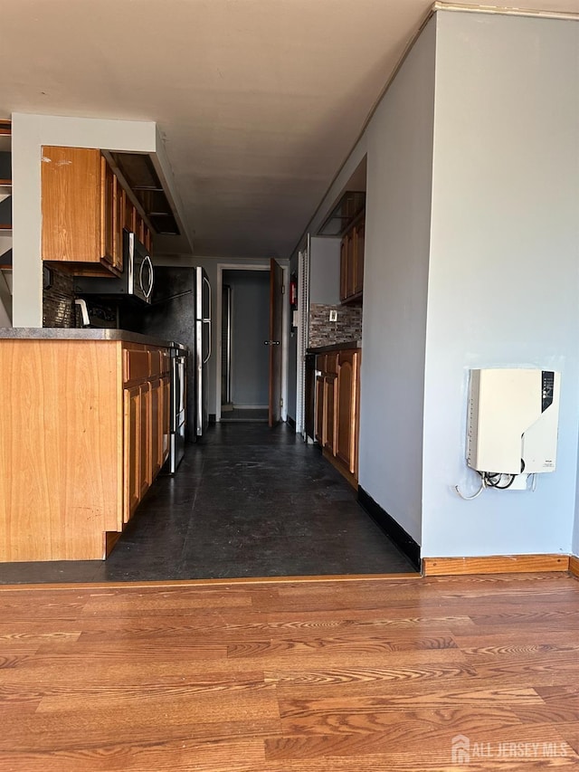 kitchen featuring heating unit, stainless steel microwave, and dark wood-style flooring