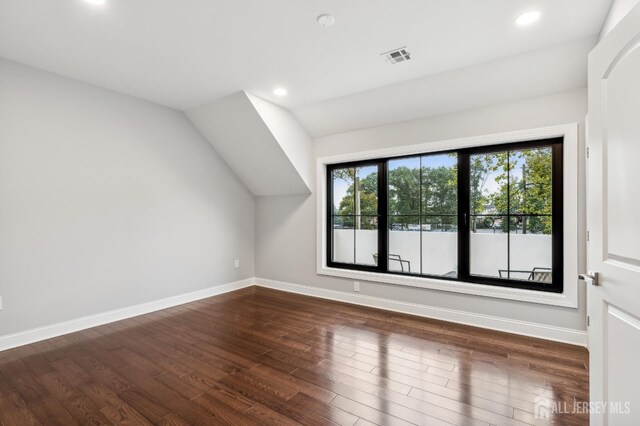 bonus room with dark hardwood / wood-style flooring and vaulted ceiling