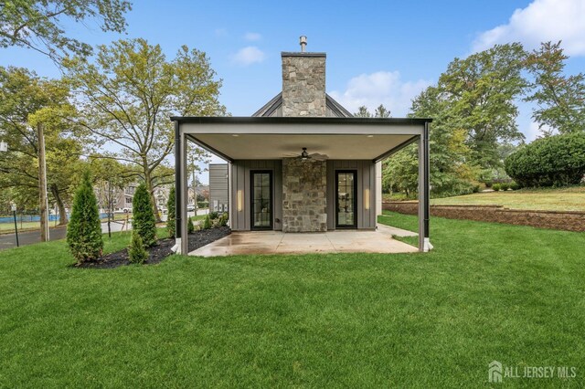 rear view of property with a lawn, ceiling fan, and a patio