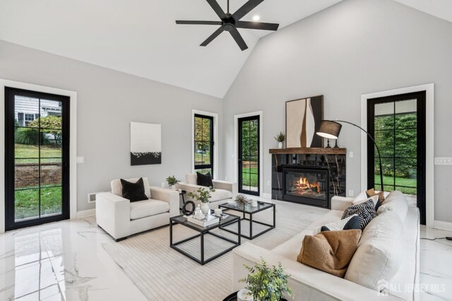 living room featuring a tiled fireplace, ceiling fan, and high vaulted ceiling