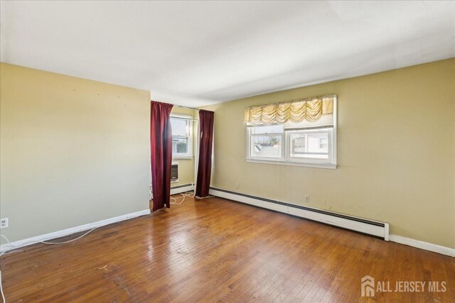 empty room featuring baseboard heating and wood-type flooring