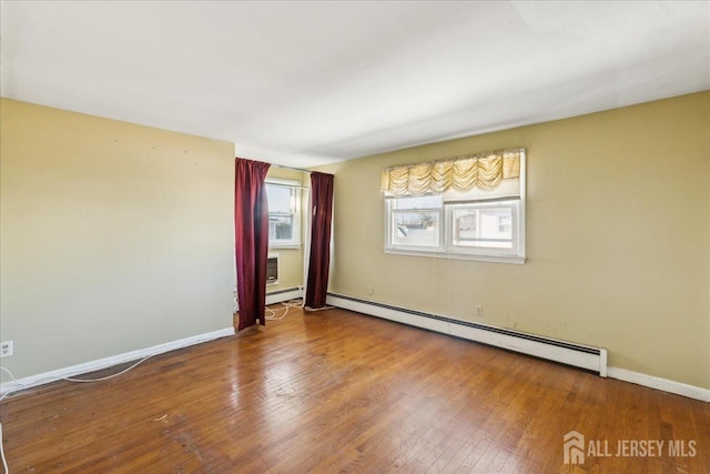 unfurnished room with a baseboard heating unit and hardwood / wood-style floors