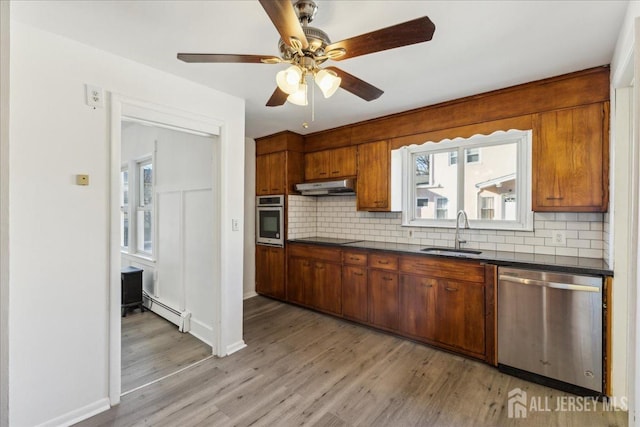 kitchen featuring stainless steel appliances, a baseboard radiator, tasteful backsplash, and sink