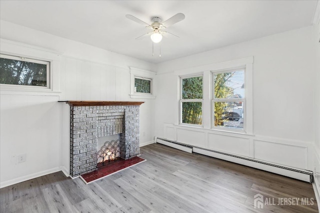 unfurnished living room with a brick fireplace, light hardwood / wood-style flooring, ceiling fan, and a baseboard radiator