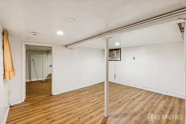 basement with an AC wall unit and wood-type flooring