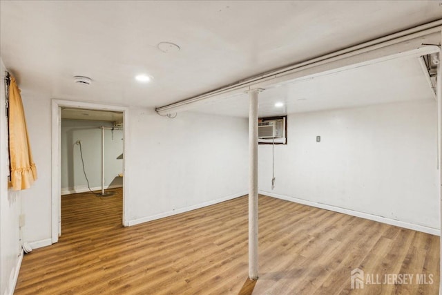 basement featuring a wall unit AC and hardwood / wood-style floors