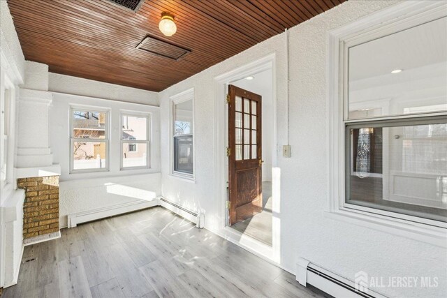 unfurnished sunroom with baseboard heating and wood ceiling