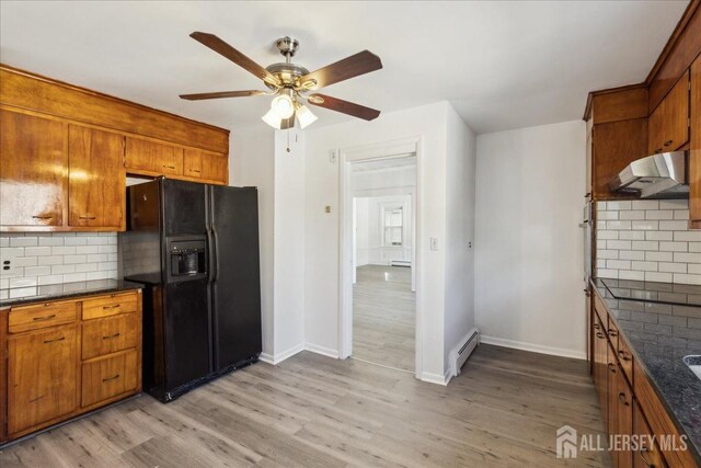 kitchen featuring black fridge, light hardwood / wood-style floors, baseboard heating, backsplash, and ceiling fan