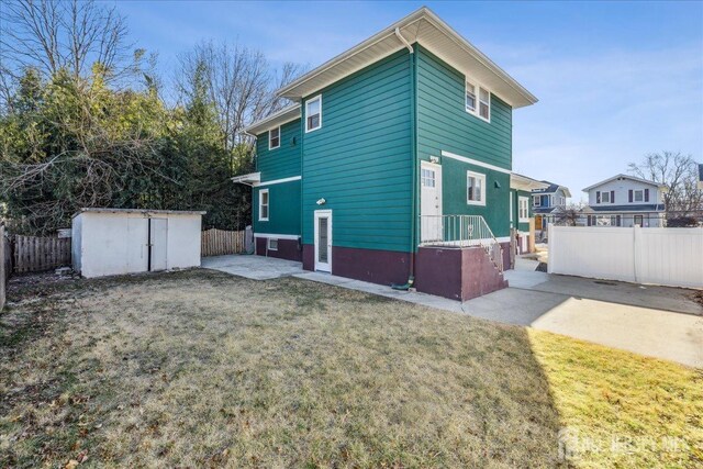 rear view of house with a shed, a yard, and a patio