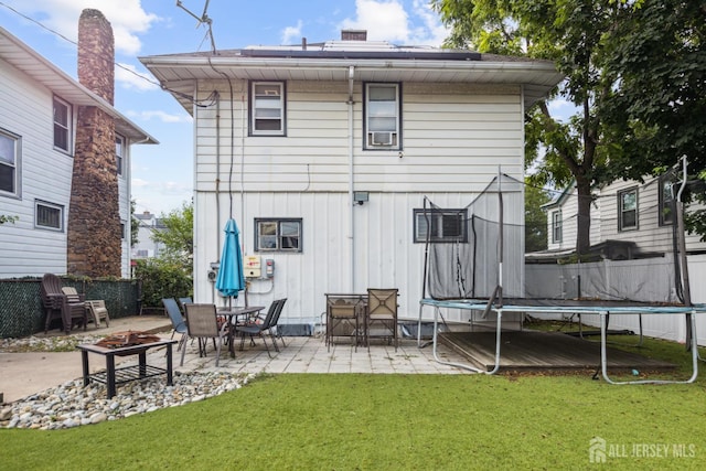 263 Bordentown Ave, South Amboy, NJ 08879 - back of property with a trampoline, a patio area, board and batten siding, and a fire pit