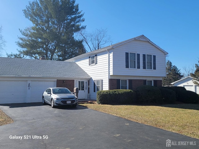 traditional-style home with aphalt driveway, brick siding, an attached garage, and a front yard